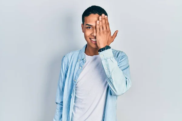 Joven Afroamericano Con Ropa Casual Cubriendo Ojo Con Mano Sonrisa — Foto de Stock