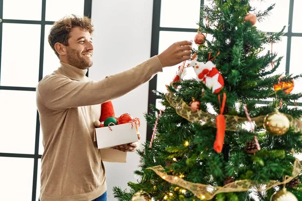 Νεαρός Ισπανός Άνδρας Χαμογελά Αυτοπεποίθηση Διακοσμώντας Χριστουγεννιάτικο Δέντρο Στο Σπίτι — Φωτογραφία Αρχείου