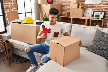 Genç İspanyol adam yeni evinde kendine güvenen bir karton kutu paketliyor.