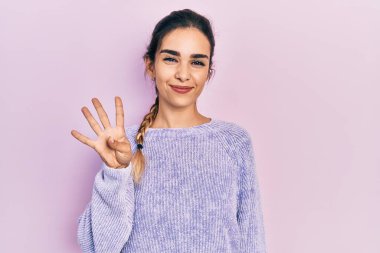 Latin kökenli genç bir kız günlük kıyafetler giyer ve parmaklarıyla dört numarayı gösterir.. 