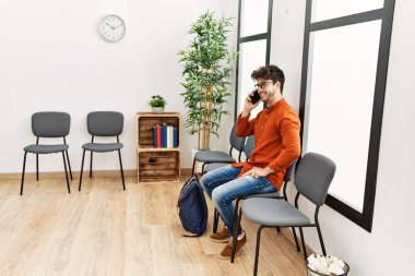 Young hispanic man smiling confident talking on the smartphone at waiting room
