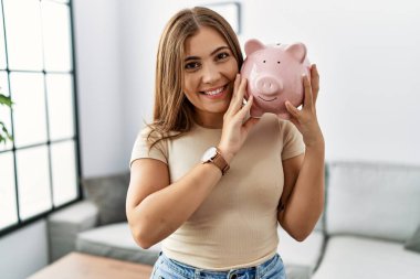 Genç İspanyol kadın gülümsüyor. Kumbarasını evinde tutuyor.