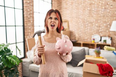 Kafkasyalı genç bir kadın yeni evinde domuz kumbarasını tutuyor kızgın ve kızgın çığlıklar atıyor sinirlenmiş ve öfkeli, öfkeyle bağırıyor.. 