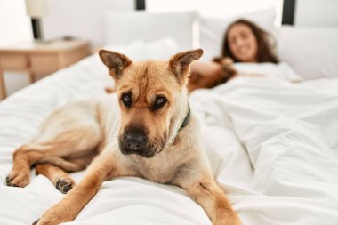 Genç İspanyol kadın yatak odasında köpeğe sarılıyor.