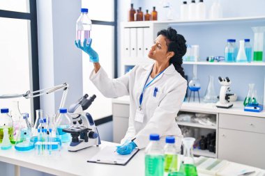Laboratuvarda sıvı ölçen bilim adamı üniforması giyen Afrikalı Amerikalı kadın.