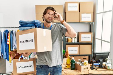 Gönüllü yardım derneği için bağış kutusu tutan yakışıklı orta yaşlı adam. Alnındaki sorun için endişeli ve stresli. Kriz için endişeli. 