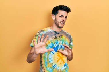 Gündelik kıyafetler giyen genç İspanyol adam tiksinti ifadesi takındı, tiksinti tepkisi yüzünden tiksinti ve korku dolu bir ifade takınıyordu. Eller havada. 