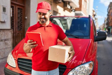 Genç İspanyol kurye sokakta dokunmatik ped paketi kullanıyor.