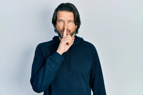 中世の白人男性は唇に指で静かにするように求めてカジュアルなスウェットシャツを着ていた 沈黙と秘密の概念 — ストック写真