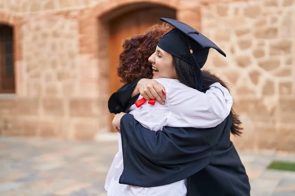 2人の女性の母親と娘がキャンパス大学で卒業証書を持って抱き合って — ストック写真