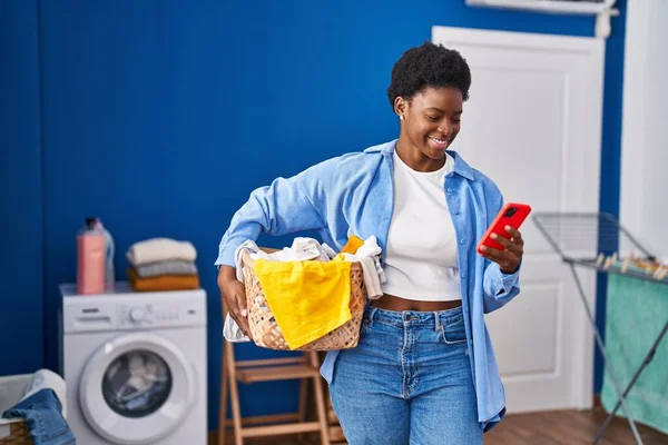 African American Woman Holding Basket Clothes Using Smartphone Laundry Room — 图库照片