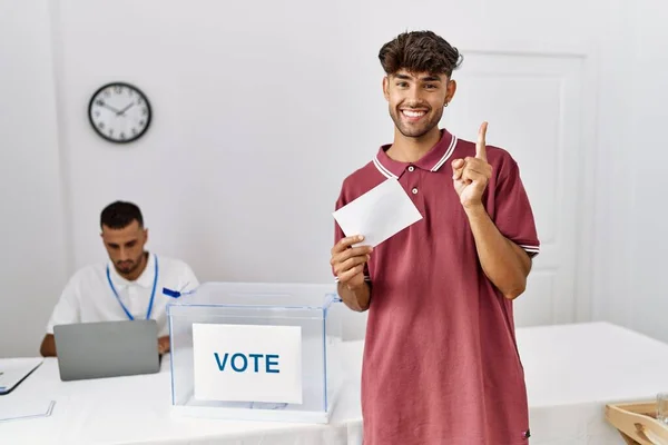 投票的年轻人把信封放进投票箱 面带微笑 高兴地手指手画脚地指向一边 — 图库照片
