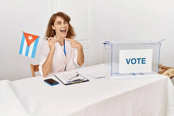 Beautiful caucasian woman at political campaign election holding cuba flag smiling happy pointing with hand and finger