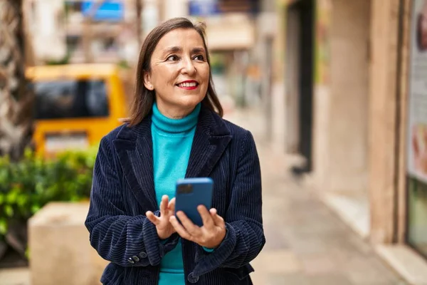 Sokakta akıllı telefon kullanan orta yaşlı bir iş kadını.