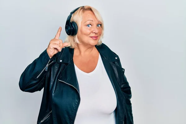 Middle Age Blonde Woman Listening Music Using Headphones Pointing Finger — Stockfoto