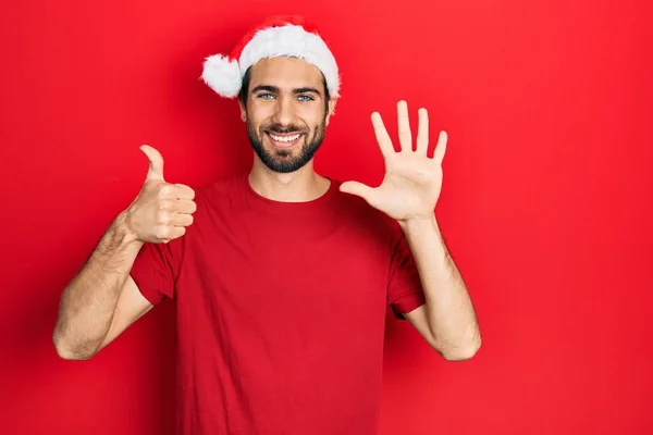 Młody Hiszpan Świątecznej Czapce Pokazuje Wskazuje Palcami Numer Sześć Uśmiechając — Zdjęcie stockowe