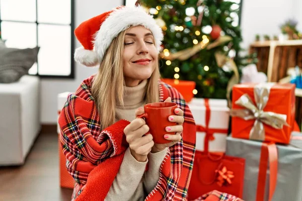 Νεαρή Ξανθιά Γυναίκα Που Πίνει Καφέ Καθισμένη Στο Χριστουγεννιάτικο Δέντρο — Φωτογραφία Αρχείου