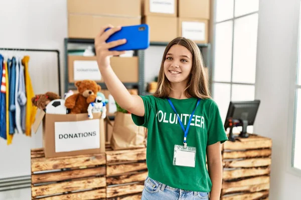 Adorable girl wearing volunteer uniform make selfie by the smartphone at charity center