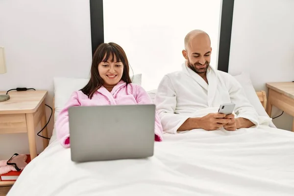 Молода Іспаномовна Пара Використовує Ноутбук Смартфон Сидячи Ліжку Спальні — стокове фото