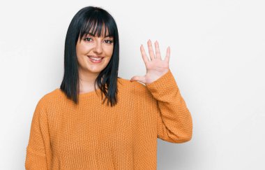 Genç İspanyol kadın gündelik kıyafetler giyer ve beş numarayı göstererek gülümserken kendinden emin ve mutluydu.. 