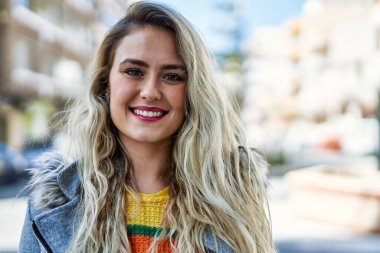 Genç sarışın kadın şehre gülümsüyor.