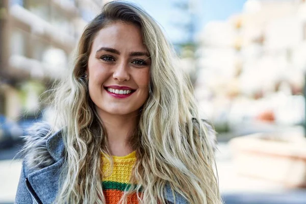 Genç sarışın kadın şehre gülümsüyor.