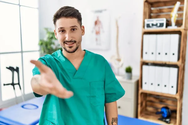 Young Physiotherapist Man Working Pain Recovery Clinic Smiling Cheerful Offering — Stockfoto
