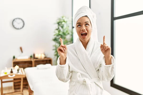 Young Brunette Woman Wearing Towel Bathrobe Standing Beauty Center Amazed — Stock Photo, Image