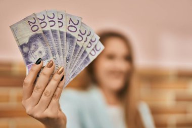 Genç sarışın iş kadını gülerek şehirde İsveç kronu banknotları tutuyor..