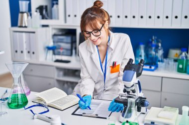 Genç kadın bilim adamı, laboratuardaki belgelere yazı yazıyor.