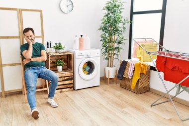 Orta yaşlı İspanyol adam evde çamaşırlarını yıkıyor..