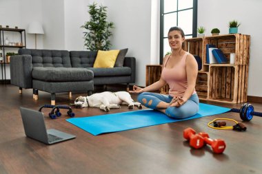 Evde yoga dersi aldığı için kendinden emin gülümseyen genç bir kadın.