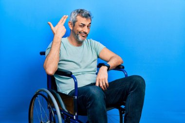 Yakışıklı, orta yaşlı, gri saçlı, tekerlekli sandalyede oturan, ateş eden ve kendini öldüren, silah gibi el ve parmakları işaret eden, intihar jesti.. 