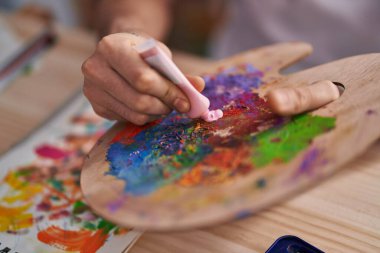 Genç Arap adam sanat stüdyosunda renkleri karıştırıyor.