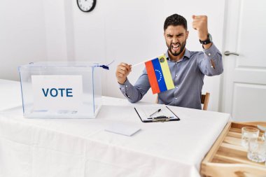 Siyasi seçim kampanyasında sakallı, elinde Venezuela bayrağı olan genç ve yakışıklı bir adam öfkeyle bağırıyor, öfkeyle bağırıyor ve el kaldırıyor. 