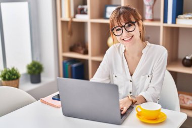 Young woman using laptop sitting on table at home