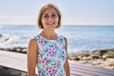 Orta yaşlı, güzel bir kadın. Deniz kenarında kendine güvenen.