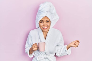 Bornoz giyen genç İspanyol kız bir fincan kahve içiyor gururla bağırıyor, zaferi kutluyor ve başarıyı kollarını kaldırarak kutluyor. 