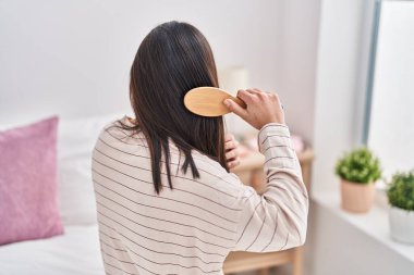 Genç İspanyol kadın yatak odasında saçlarını tarıyor.