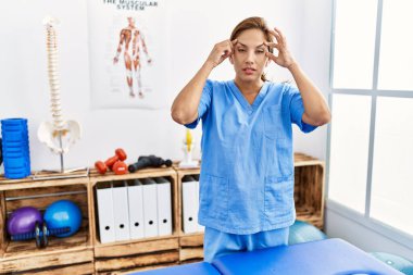 Orta yaşlı İspanyol fizyoterapist kadın. Ağrı kesici kliniğinde çalışıyor. Gözlerini parmaklarıyla açmaya çalışıyor. 