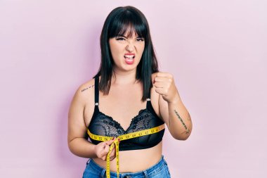 Göğüs ölçüsü kullanan genç İspanyol kadın öfkeyle bağırıyor, öfkeyle bağırıyor ve el kaldırıyor. 