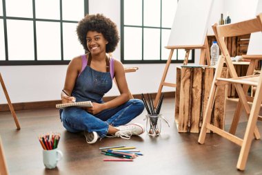 Genç Afrikalı Amerikalı kadın sanat stüdyosunda kendine güvenen bir çizim yapıyor.