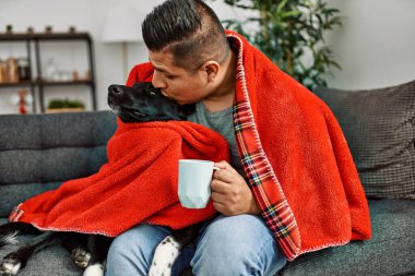 Genç İspanyol adam battaniyeyle örtülmüş evde bir fincan kahve içiyor..