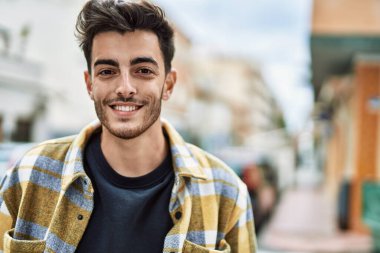 Yakışıklı İspanyol adam şehirde mutlu ve kendinden emin gülümsüyor.