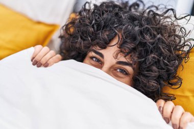 Orta Doğulu genç bir kadın yatak odasında ağzını kapatıyor.