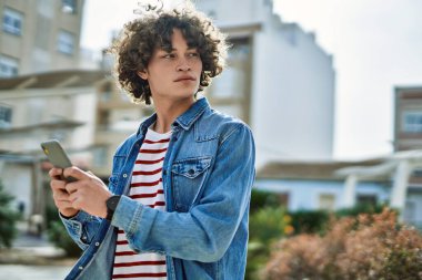 Genç İspanyol adam şehirde akıllı telefon kullanıyor.