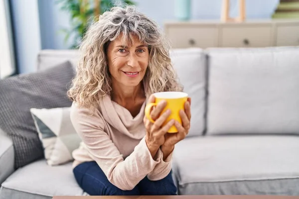 Kobieta Średnim Wieku Pije Kawę Siedząc Kanapie Domu — Zdjęcie stockowe
