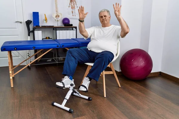 Homem Caucasiano Sênior Clínica Fisioterapia Usando Exercitador Pedal Mostrando Apontando — Fotografia de Stock