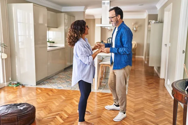 Middle age hispanic couple smiling confident dancing at home