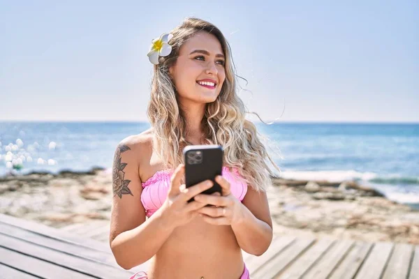 비키니를 해변에서 스마트폰을 사용하는 — 스톡 사진